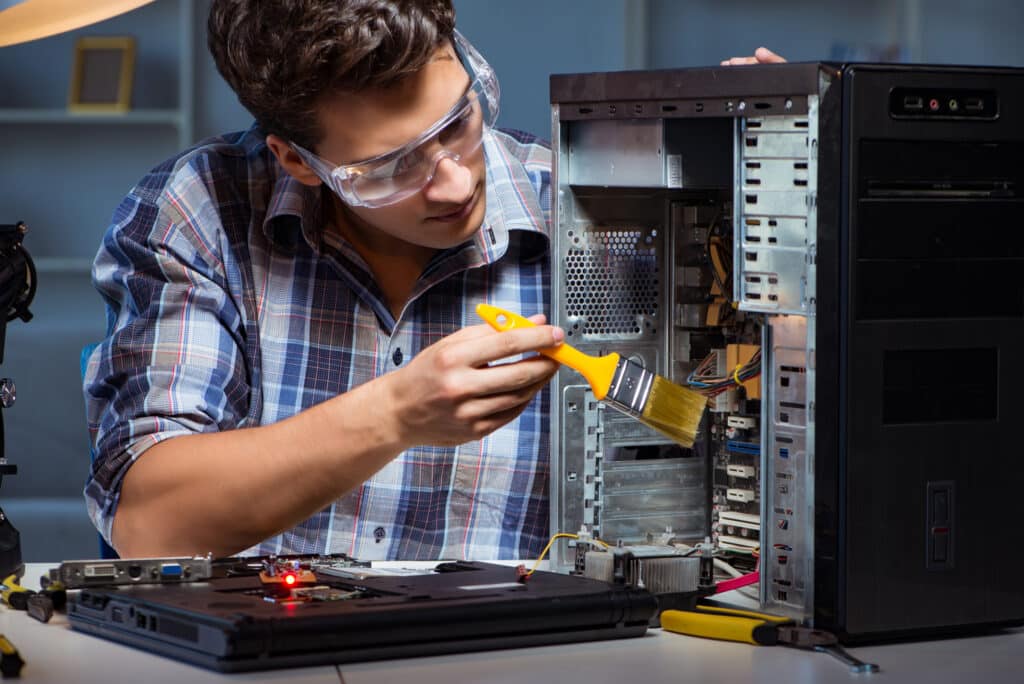 Computer repair man cleaning dust with brush